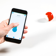 Kırmızı bir Sphero Mini robot oyuncağı süren joystick sürüş moduyla bir telefonu tutan el.