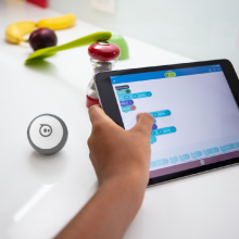 Kursta bir Sphero Mini oyuncak robotu kodlamak için Sphero Edu uygulamasında blok programlamayı kullanan çocuk.