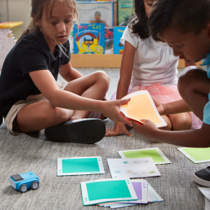 Kids collaborating to solve problems with a coding robot toy.