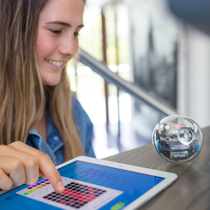 Gülümseyen ve ipad ile Sphero BOLT STEM robot oyuncağı kodlayan kız.