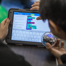 Bir ipad üzerinde Sphero BOLT STEM robotu kodlayan öğretmen ve öğrenci