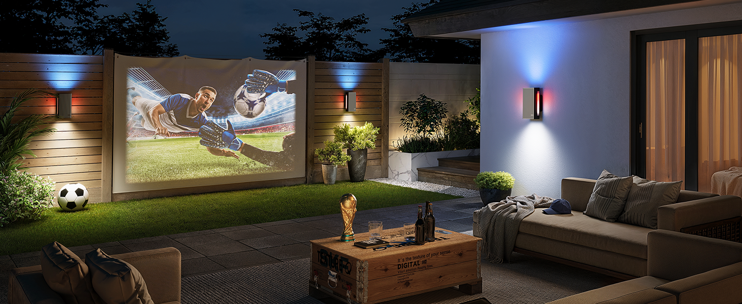 Duvara yansıtılmış bir ekrana sahip açık hava ev sinema sistemi, rahat oturma alanı, atmosferik aydınlatma ve görünürde bir futbol topu bulunan peyzajlı bir bahçe.