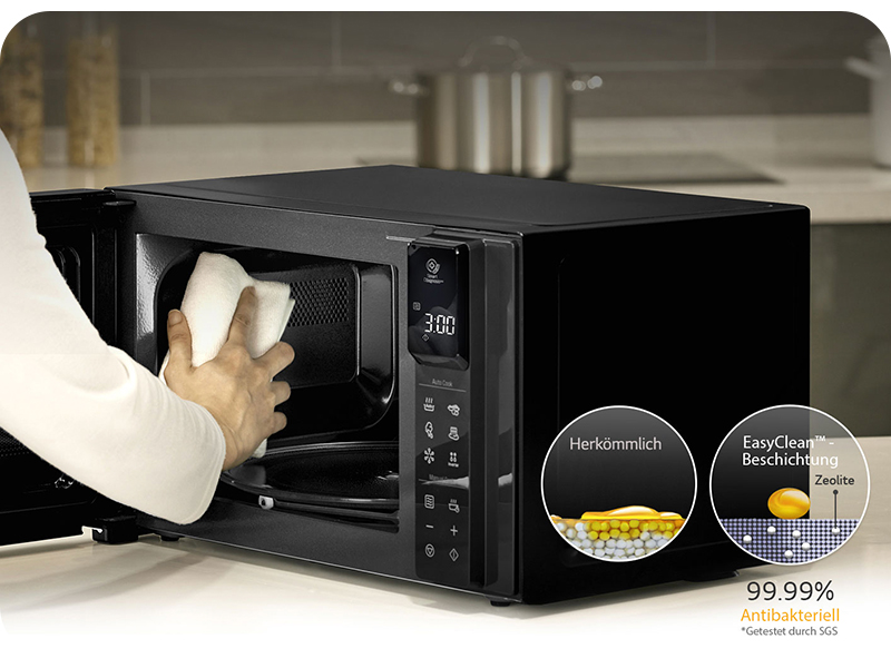 Verimliliği %99,99'u gösteren iki dairesel göstergeye sahip siyah bir mikrodalga fırına doğru uzanan el.