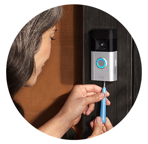Kahverengi uzun saçlı bir kadın, Ring Battery Video Doorbell Pro'nun ön panelini tekrar takıyor ve cihazın alt kısmındaki vidayı mavi bir tornavidayla sıkıyor.