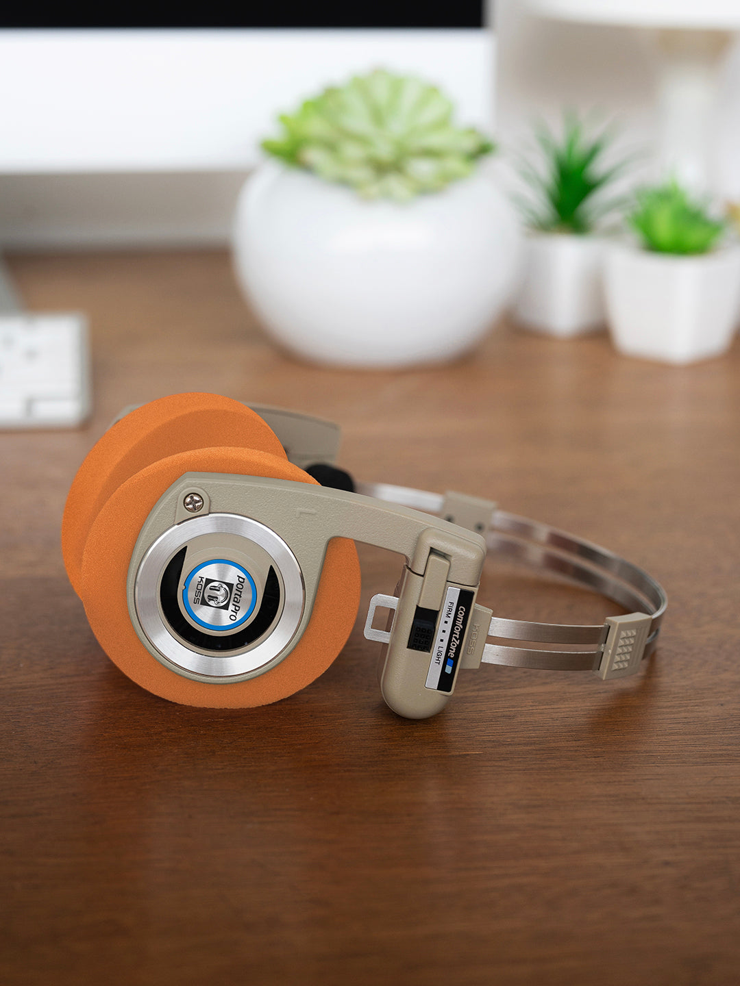 Koss Porta Pro Wireless in Rhythm Beige laying on a desk with Orange Oversized Cushions