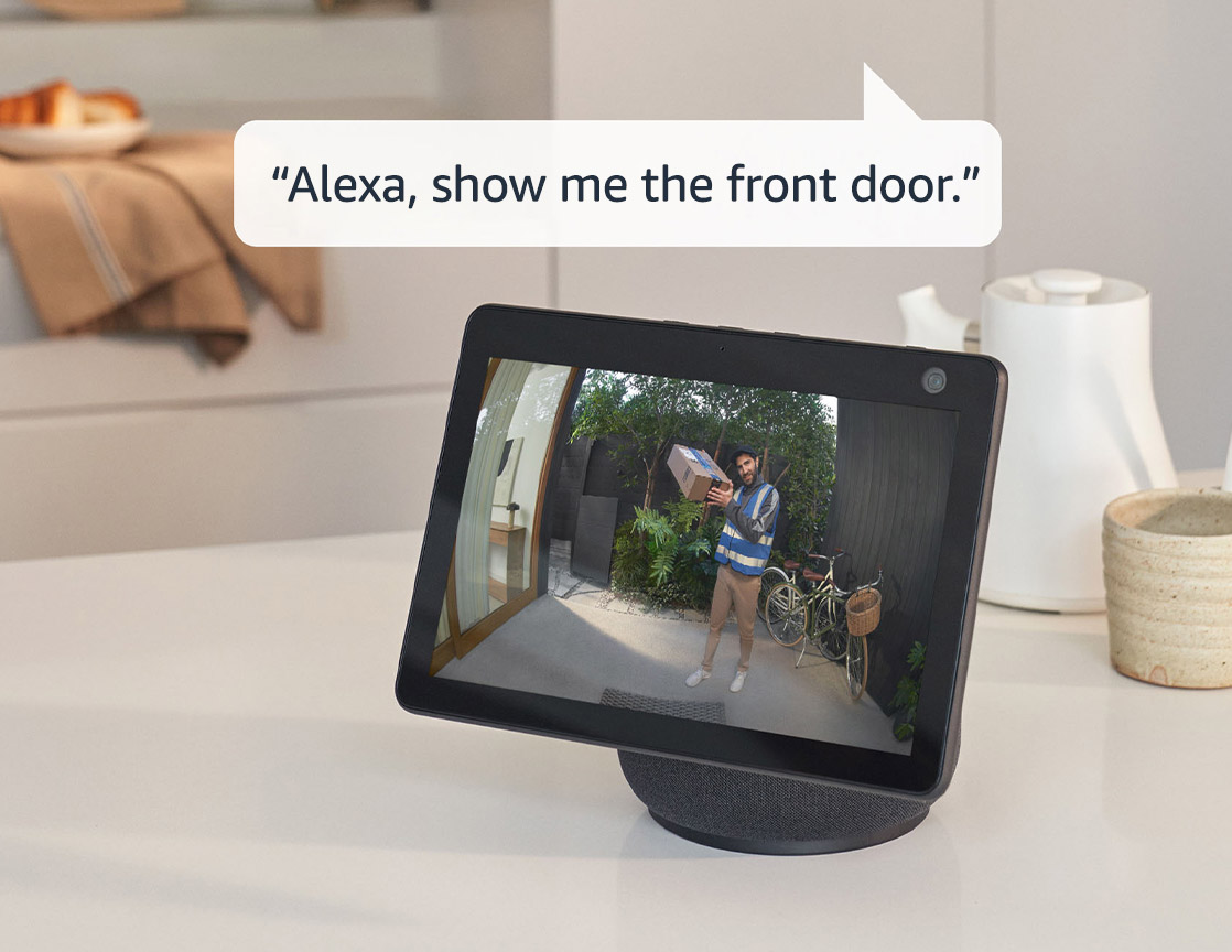 Mutfak tezgahındaki Echo Show 10, ön kapıda bir kuryenin elinde bir paket tuttuğunu gösteriyor. Cihazın üzerindeki konuşma balonunda ise 