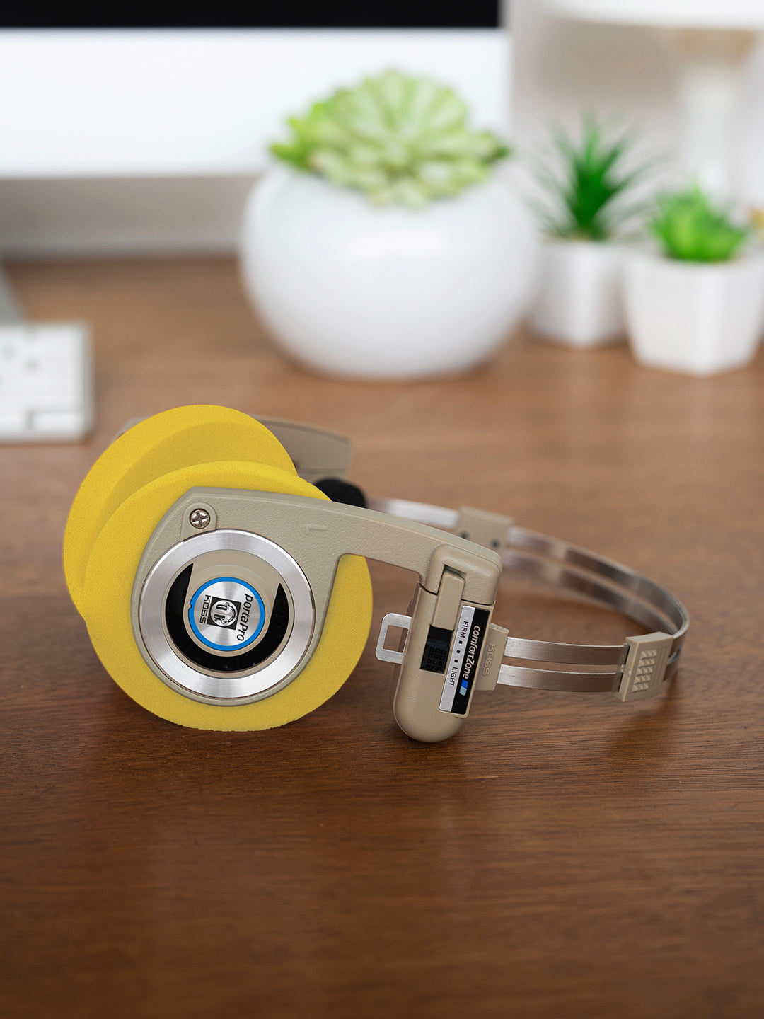 Koss Porta Pro Wireless Rhythm Beige laying on a desk with Yellow Oversized Cushions