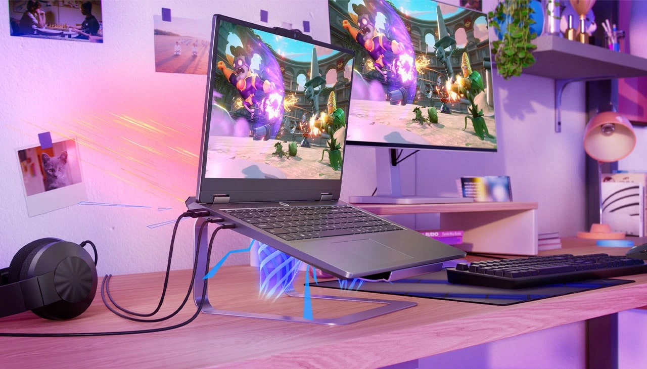 Lenovo LOQ Essential 15IRX11 oyun dizüstü bilgisayarı, kulaklık, klavye ve monitör ile masa üzerinde bir stand üzerinde - sol önden görünüm, kapak açık, ekranda bir video oyunu ekranı ile.