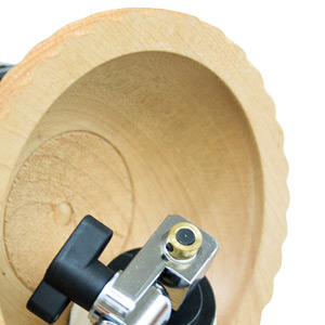 Merkezinde delik bulunan bej renkli dairesel bir cismin yakın çekim görüntüsü; cismin yüzeyine siyah bir topuz ve metal bir bağlantı parçası takılmıştır.