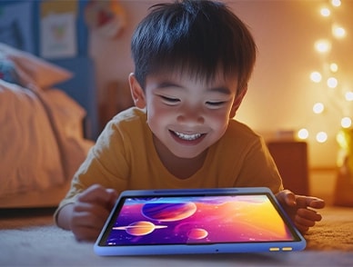 Yerde yatan gülümseyen bir çocuk, rahat ve yumuşak ışıklı bir odada canlı uzay temalı bir animasyonu izlemek için Lenovo Tab kullanıyor.