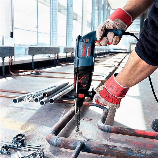Bir inşaat alanında güvenlik ekipmanı takan bir kişi metal bir boruyu delmektedir.