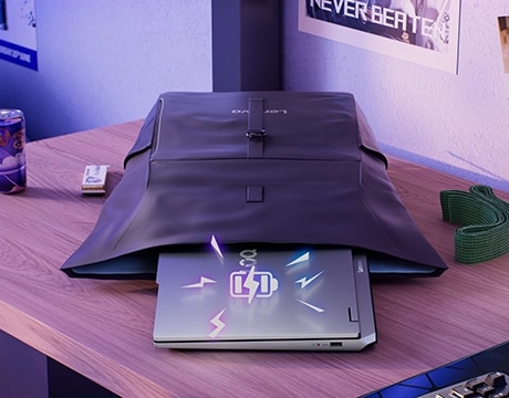 Lenovo LOQ Essential 15IRX11 oyun dizüstü bilgisayarı, kapağın üzerine yerleştirilmiş bir pil şarj simgesi grafiği ile masanın üzerindeki açık bir sırt çantasından çıkıntı yapıyor.