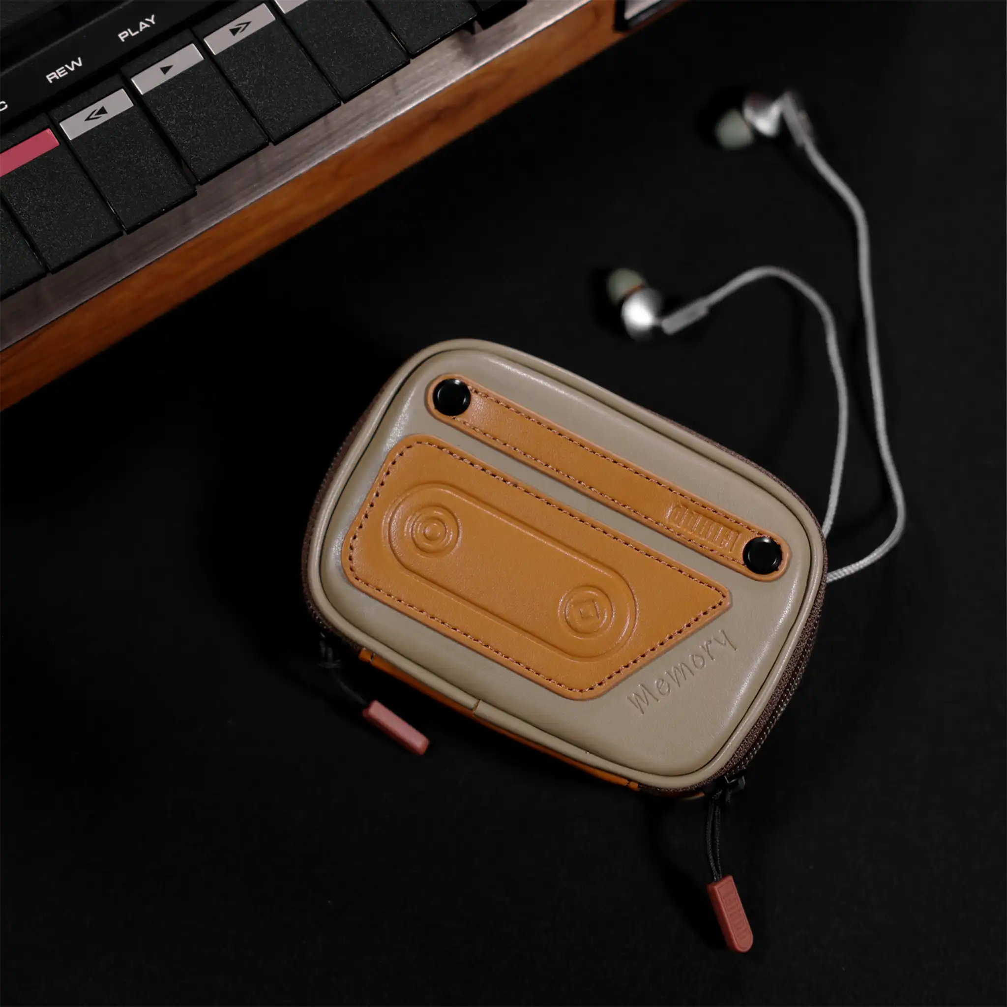 ddHiFi CZ120 retro earphone case lying on black backdrop with earphones coming out next to retro music device