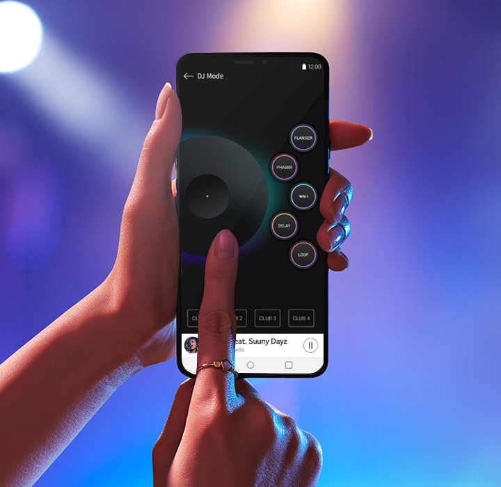 Görüntüde bulanık bir parti mekanı arka planı görülüyor. Bir el elinde bir akıllı telefon tutarken diğer el ekrana dokunarak DJ uygulamasını gösteriyor.
