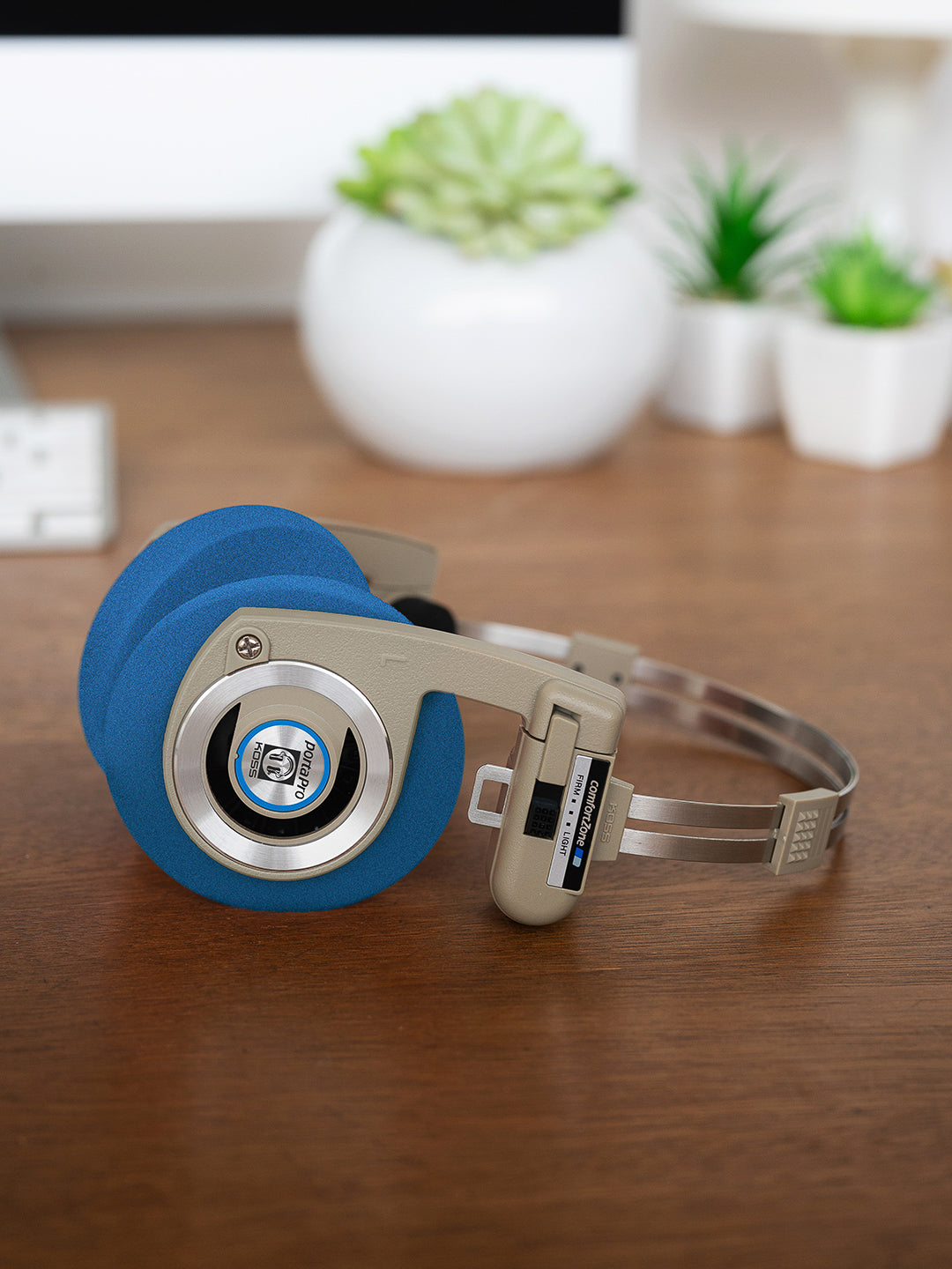 Koss Porta Pro Wireless Rhythm Beige laying on a desk with Blue Oversized Cushions