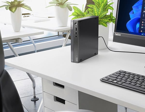 Lenovo ThinkCentre Neo 50q Gen 4 Tiny (Intel)'in, bir ofis masasının üzerinde, monitör ve klavyenin (ayrı satılır) yanında dikey olarak durduğu yakın çekimi