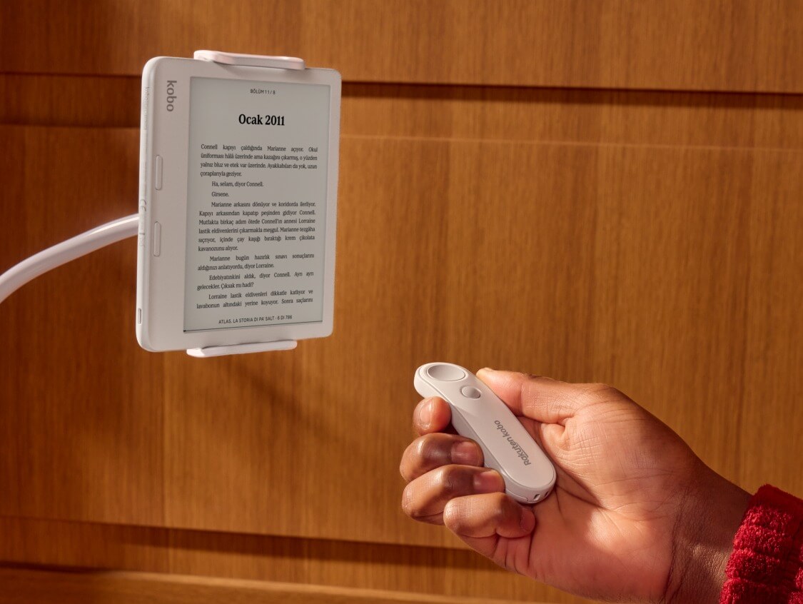 Beyaz bir Kobo Remote, birinin sağ elinde, bükülebilir bir stant üzerindeki beyaz bir Kobo Libra Colour e-kitap okuyucusuna doğru işaret ederken gösteriliyor.