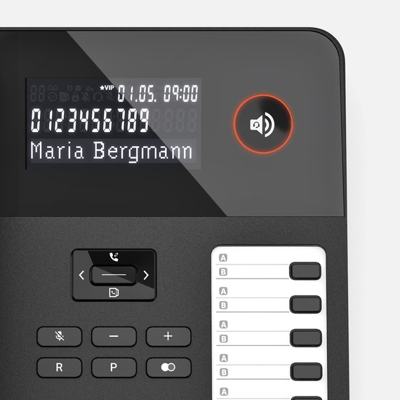 Ekranı ve fonksiyon tuşları olan bir masa telefonunun yakın çekiminde 'Maria Bergmann' ismi yer alıyor.