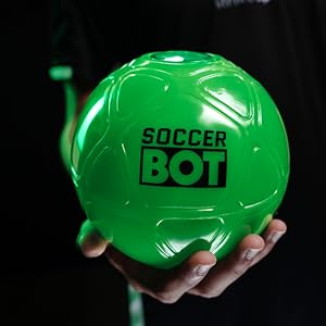 Metinde "FUTBOL ROBOTU" yazıyor. Koyu bir arka plana karşı tutulan, açık yeşil, küresel bir oyuncak veya top üzerinde siyah yazı bulunuyor.