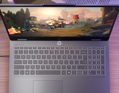 Masa üzerinde Lenovo LOQ Essential 15IRX11 oyun dizüstü bilgisayarı - yukarıdan görünüm, ekranda oyun ekranı ile kapak açık.