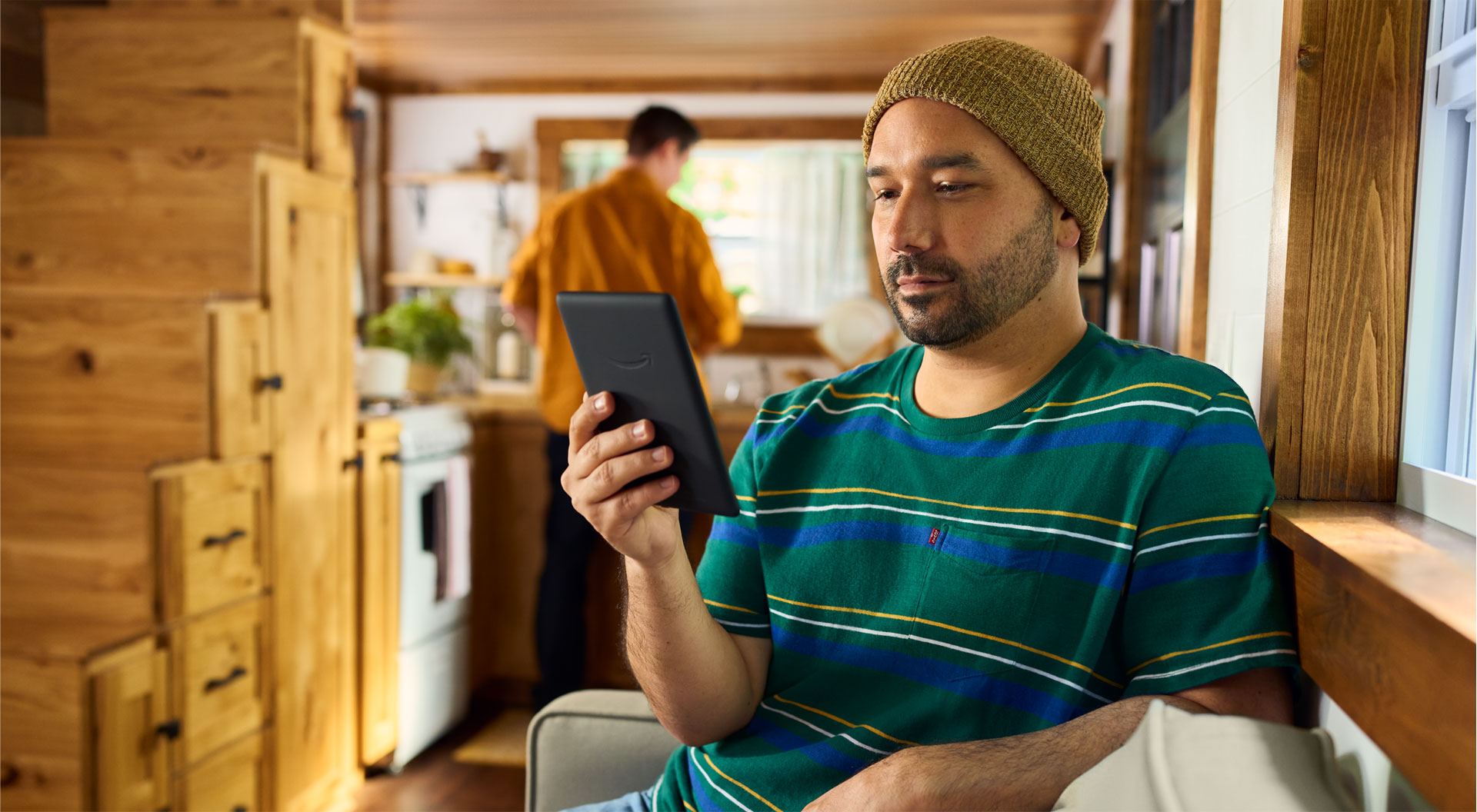 Adam bir kanepede otururken Kindle Paperwhite Signature Edition'ı okuyor.