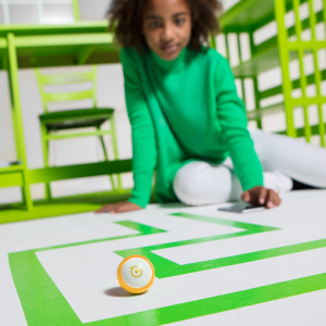 Bir labirentte Sphero Mini STEM robotunu kodlayan kız.